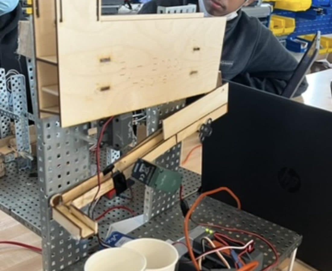 Wooden hopper and VEX marble sorter with colored cups on a green gear.